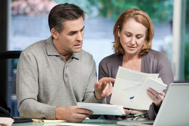 Couple looking at credit card statements and home equity loan paperwork.