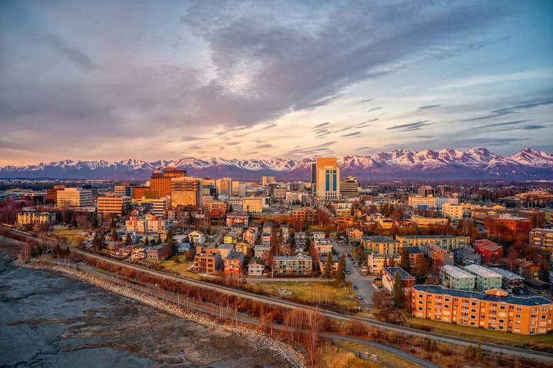 Sunset skyline view of Anchorage Alaska with mountains in the background.