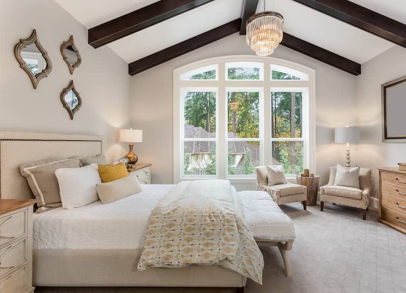  Furnished primary bedroom with vaulted ceilings and a grey color theme.