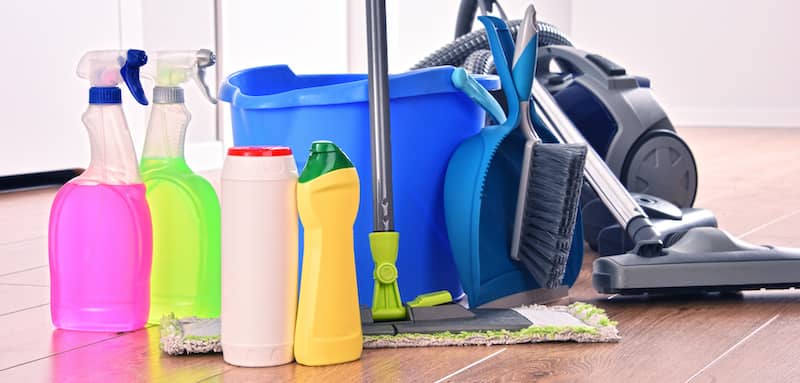 Set Vacuum, mop, and various cleaning supplies on hardwood floor.