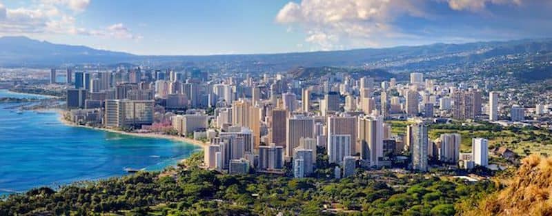 Coastline view of Honolulu with rainbow arching over aquamarine water.