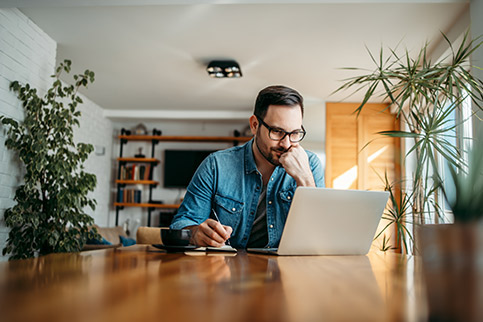 Man on laptop at table drafting a financial hardship letter.