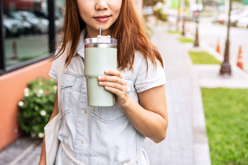 Woman walking down street with tumbler.