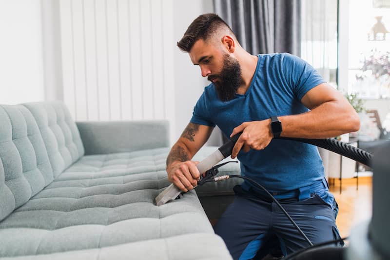 Man steam cleaning couch.