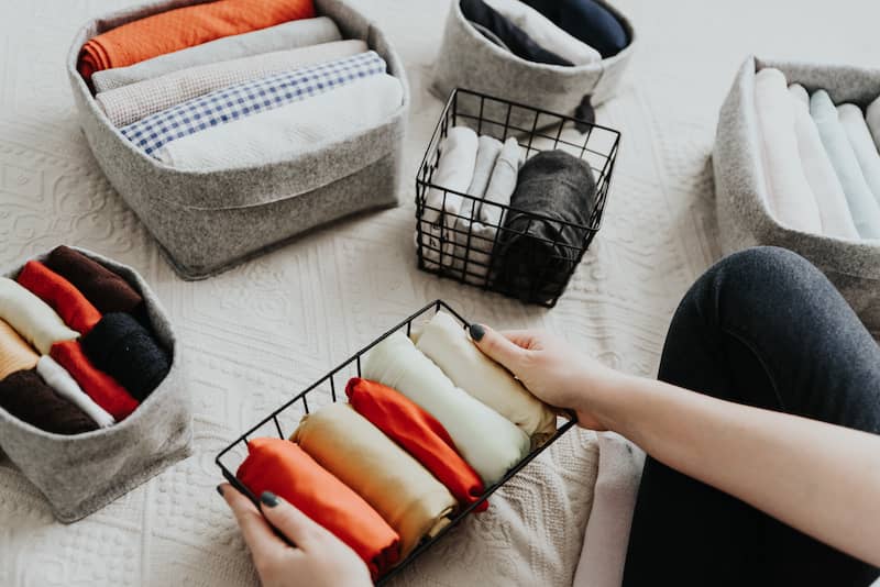 Woman organizing linens in various small bins for closet.