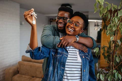 Happy couple embracing with keys to their new home.