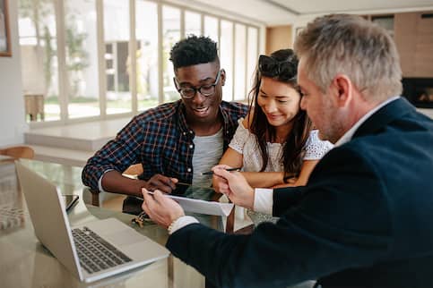 Group of three people meeting in an office and looking over a document together.