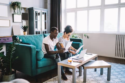 African American couple looking over paperwork together in living room.
