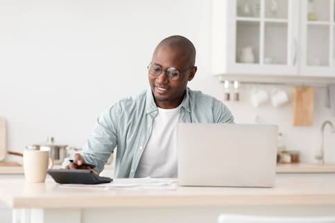 African American man using laptop at home on kitchen counter.