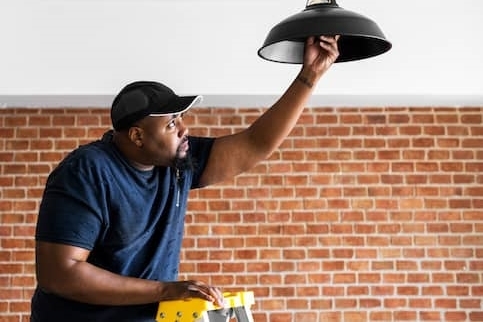 African-American man changes lightbulb.
