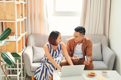 Asian couple pay bills on their computer.