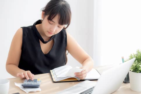 Asian woman with calculator and notes.