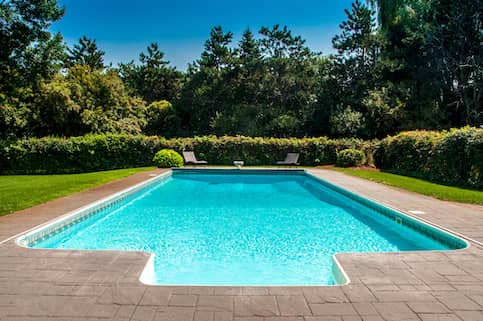 Unique shaped in ground backyard pool.