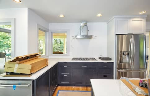 Large kitchen with white countertops in the process of being remodeled.