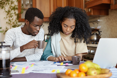 Black Couple Using Calculator While Paying Bills