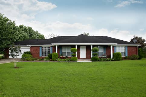 Brick ranch home with white door and blue shutters.