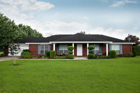 Brick ranch house with large windows.