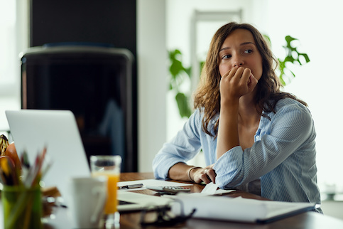 Woman looking pensive at home office desk.