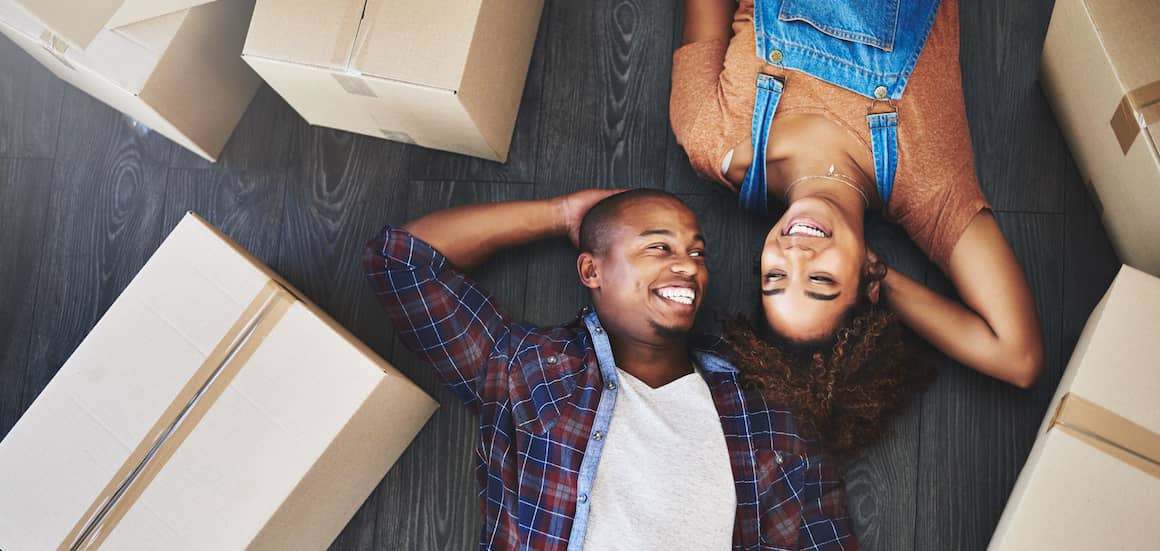 Couple laying on floor by moving boxes.