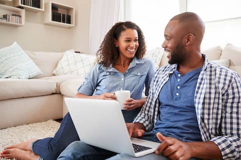 African American couple on the couch together using a laptop.