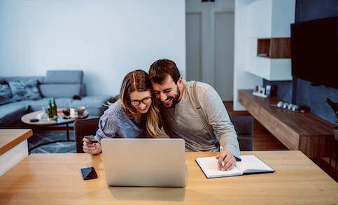 Couple smiling and embracing while making a transaction online.