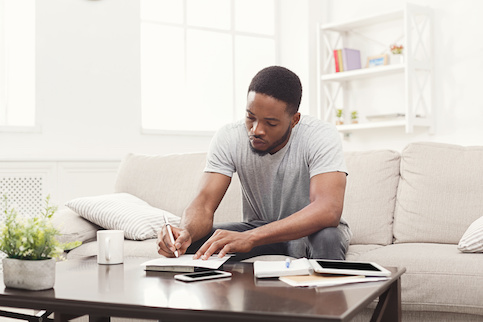 Man working on finances from couch at home.