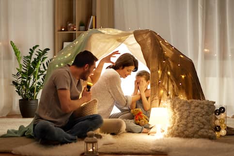 Family of three sitting together in an indoor children's tent.