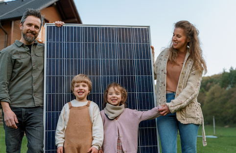 Family posing with solar panel.