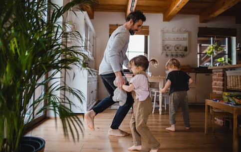 Happy father with two young children dancing in home.