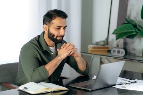 Man sitting at his desk with his laptop seeming focused.