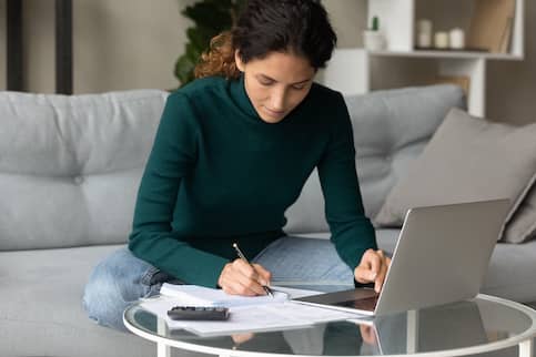 Focused Young Woman Writing A Budget