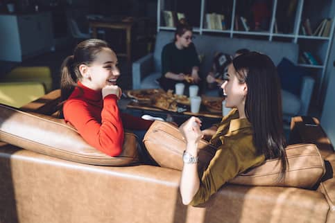 Group of friends hanging out at home eating pizza and talking.