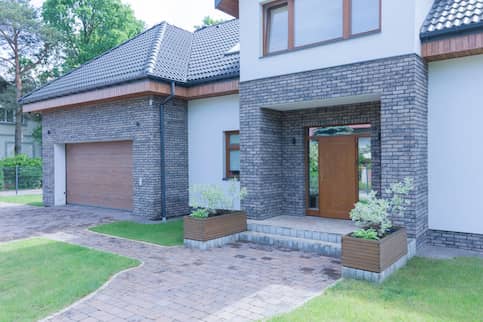 American house with gray brick walls and a brick driveway.