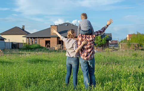 Happy family looking at new home almost done with construction.