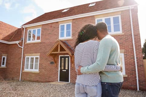 Couple embracing while looking at home for sale.