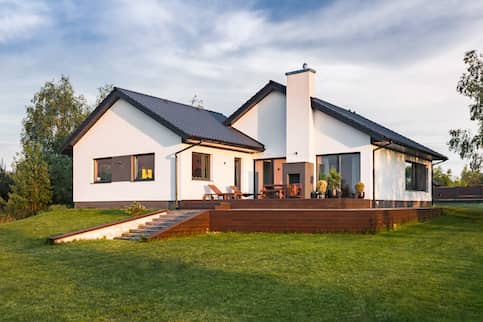 White contemporary house with large green lawn yard.