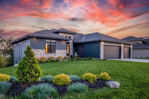 House with large lawn and garden under a saturated, colorful sky.