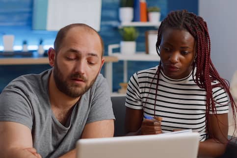 Interracial couple paying taxes on computer.