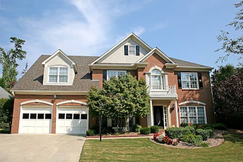 Large American home in the suburbs with a large yard and shrubs.