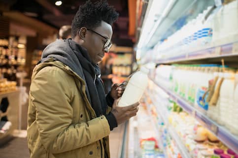 A man in the grocery store checking the price of milk.