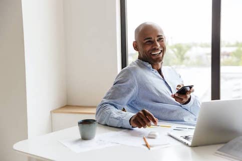 African American man browses computer and phone at the same time.