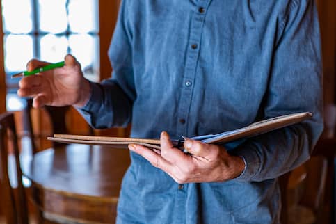 Man with notebook appraises house.