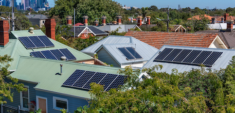 Many homes in neighborhood with solar panels on roofs.