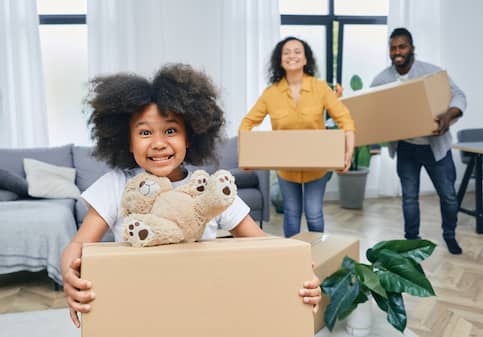 African American family moving into a new home carrying boxes happily.