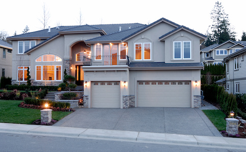 Two story grey new construction home with side by side garages and is lit from within.