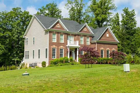 New construction three story brick home with dormers and American flag hanging.