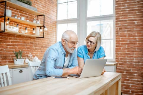 Older couple looking at laptop in their loft kitchen. 