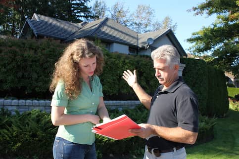 Older Man Showing A Young Woman Papers In front Of A House