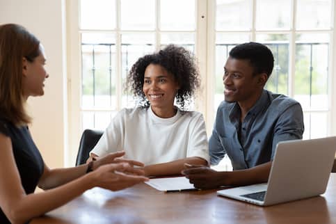 Realtor sitting with young couple in a discussion.