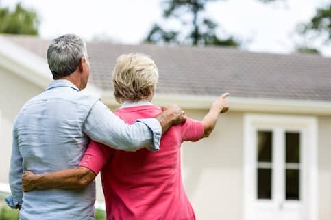 Senior couple looking at new home together from outside.